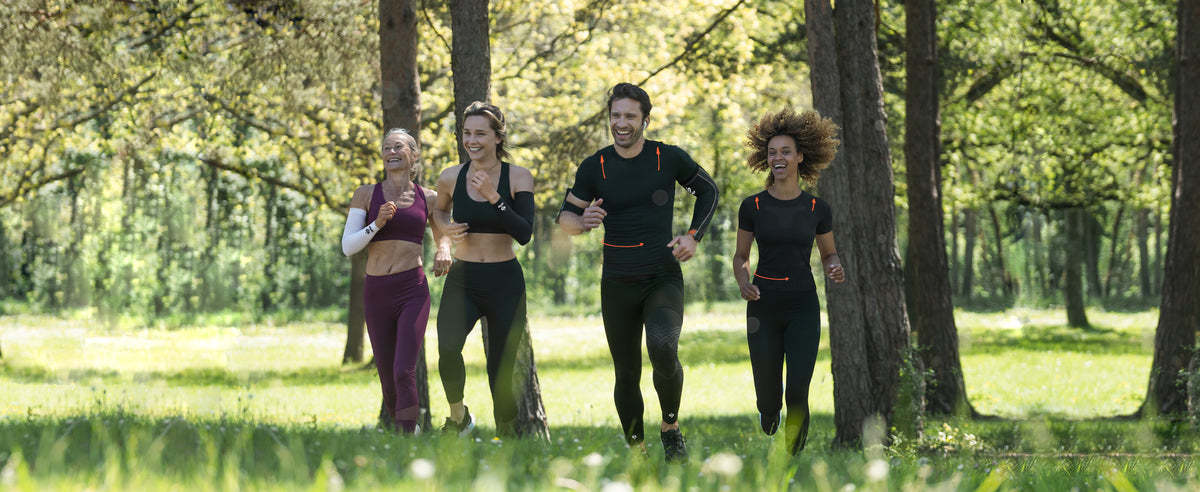 4 sportifs en train de courir en forêt avec des vêtements skinup compression