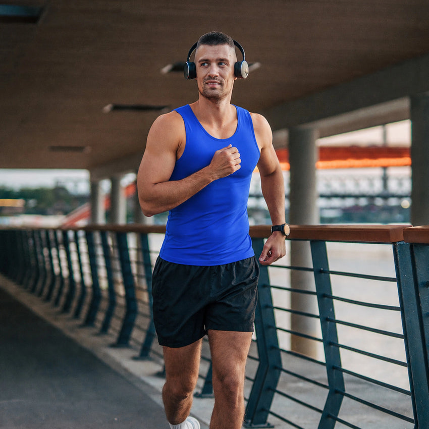Homme en débardeur bleue de sport faisant un jogging sur un pont